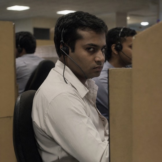 A man in a call centre cubicle wearing a headset